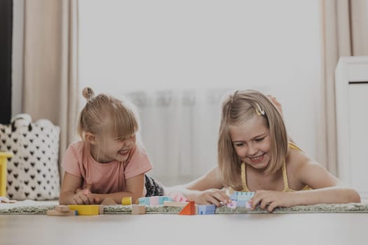 Children playing with colorful toys. Kids sitting on carpet at home bedroom or kindergarten. Development of fine motor skills, imagination, logical thinking concept. Educational eco-friendly games