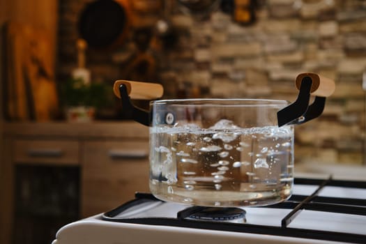Water boiling in transparent glass pot on stove