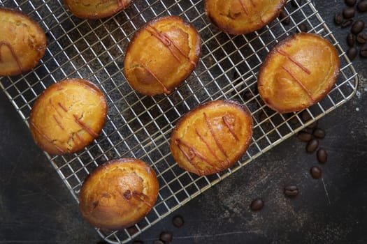 Pasticciotto leccese pastry filled with egg custard cream and sour cherry jam, on a cooling backing rack on a dark table, copy space, top view. Typical apulian breakfast