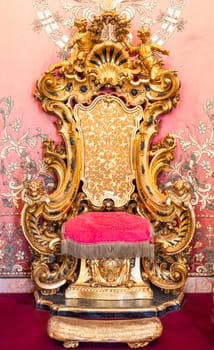 Isola Bella, Italy - 1 August 2023: antique throne in gold and red velvet. Old royal chair, luxury vintage.
