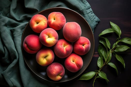 fresh ripe peaches with leaves in a bowl on a wooden table, top view
