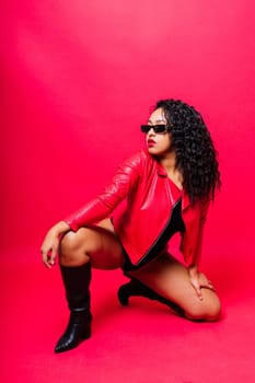 Sensual beautiful african ethnic woman in bodysuit posing in studio isolated red white background