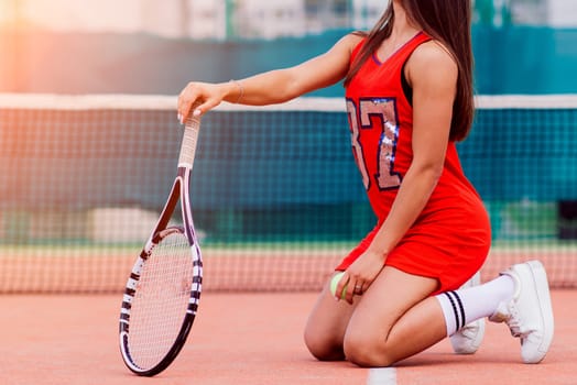 Beautiful female tennis player on tennis court in red dress.