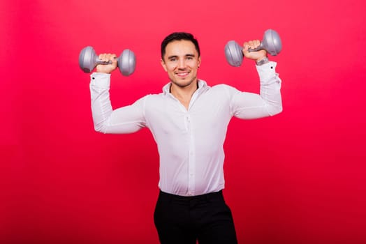 Business man with fitness dumbbells wear shirt. Studio shoot on red background
