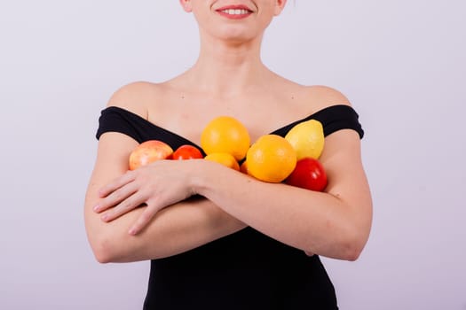 Smiling cool girl in a sun glasses in black swimsuit posing with fruits and laughing.