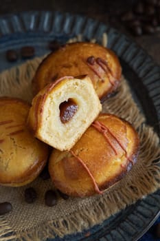 Pasticciotto leccese pastries on a dark blue plate on dark table, typical apulian breakfast, close up. Table decorated with coffee beans and juta