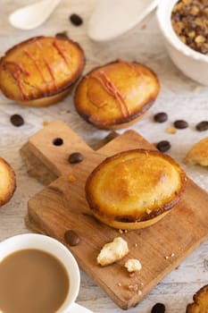 Pasticciotto leccese pastry filled with egg custard cream on a wooden board on white table, apulian breakfast, top view. Typical sweet from Lecce, Italy.