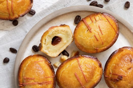 Pasticciotto leccese pastry filled with egg custard cream and sour cherry jam. Whole and half pasticiotties on a plate served for typical apulian breakfast, top view. Table decorated with coffee beans