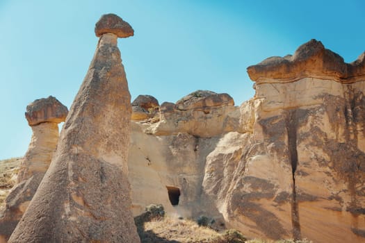 Unique geological rock formations Fairy Chimneys in Cappadocia against blue sky in summer. Popular touristic area in Goreme, Nevsehir, Turkey