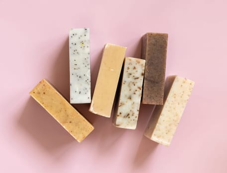 Beige and brown handmade soap bars on light pink top view, copy space. Natural herbal products for Spa and skin care. Using organic handmade skincare products in everyday routine