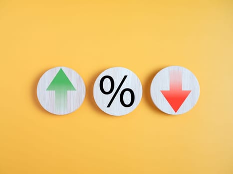 Interest rate financial and mortgage rates concept. Circle wood with icon percentage symbol and arrow up and down direction on yellow background.