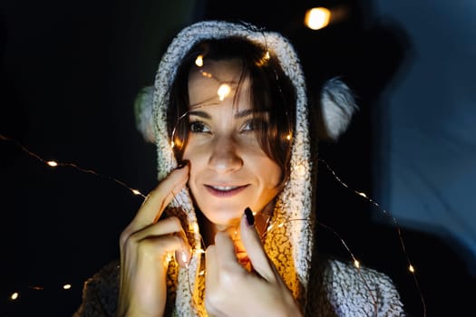 Portrait of a young woman in a room in a hood decorated with a garland