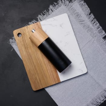 Wooden kitchen board and pepper mill on the table, top view