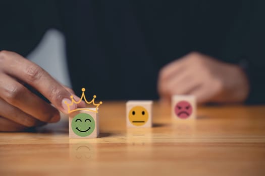 Emotion smiley face selected by a businessman's hand on a wooden cube represents the best customer experience. Satisfaction survey and feedback concept. 5-star satisfaction is guaranteed.