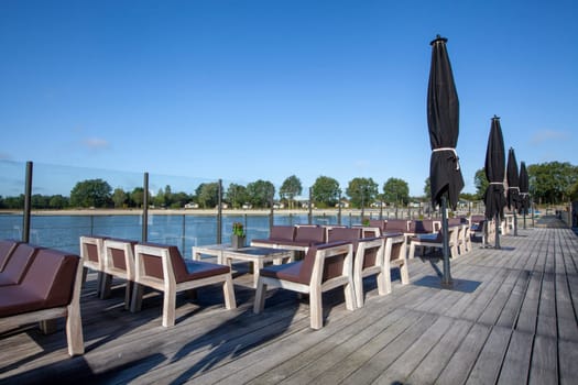 beach chair and black umbrella on the floor with lake view and a blue sky