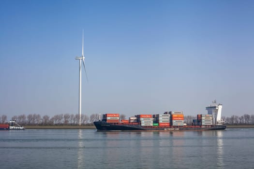 Netherlands, New Waterway. Container ship in front of modern windmill shipping, transport and heavy industry nera Maasvlakte 2.