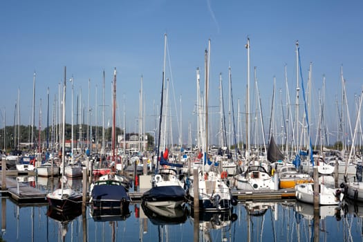 Sailboat harbor, many beautiful moored sail yachts in the sea port, modern water transport, summertime vacation, luxury lifestyle and wealth concept