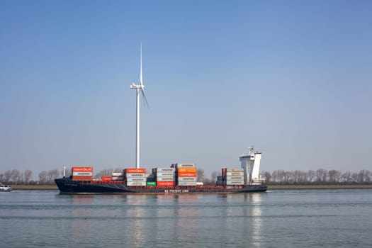 Netherlands, New Waterway. Container ship in front of modern windmill shipping, transport and heavy industry nera Maasvlakte 2.