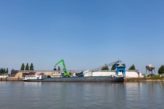 Loading barge with sand and rubble on a small berth. Freight transport logistics