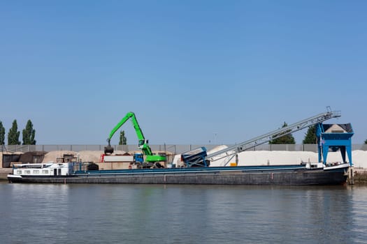 Loading barge with sand and rubble on a small berth. Freight transport logistics