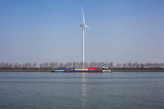 Netherlands, New Waterway. Container ship in front of modern windmill shipping, transport and heavy industry nera Maasvlakte 2.