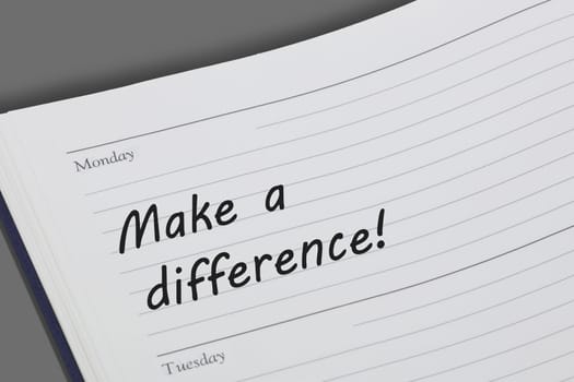 A Make a difference concept diary reminder open on a desk