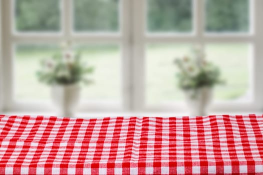 Empty table product. Closeup of a empty red tablecloth or napkin over abstract blurred bright windows background. Template for food and product display montage.