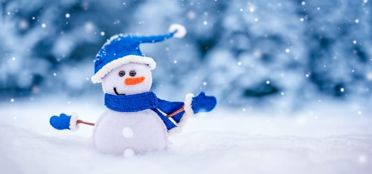 Little handmade snowman on the white snow on blue background. Beautiful panoramic view.