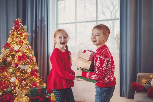 Cute boy giving gift boxes to smiling girl. Concept of the Christmas, New Year and family holidays together.