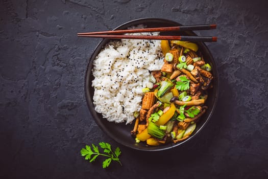 Stir-fry with mushrooms, vegetables and rice on dark background. Asian style food