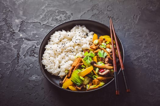 Stir-fry with mushrooms, vegetables and rice on dark background. Asian style food
