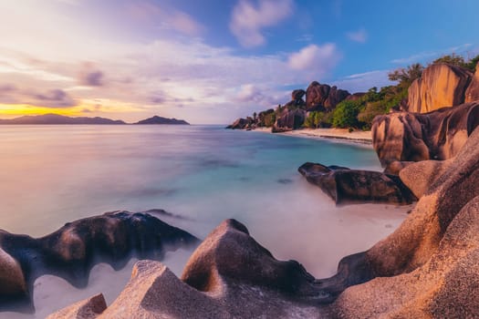 Beautifully shaped granite boulders and a dramatic sunset at picture perfect tropical Anse Source d'Argent beach, La Digue island, Seychelles.
