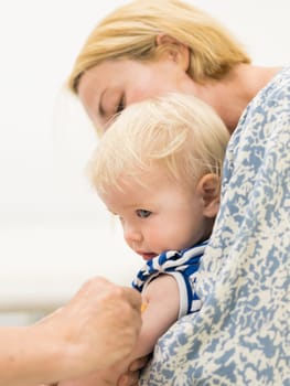 child beeing vaccinated by pediatrician in presence of his mother. Preventive vaccination against Diphtheria, whooping cough, tetanus, hepatitis, haemophilus influenzae, pneumococcus, poliomyelitis.
