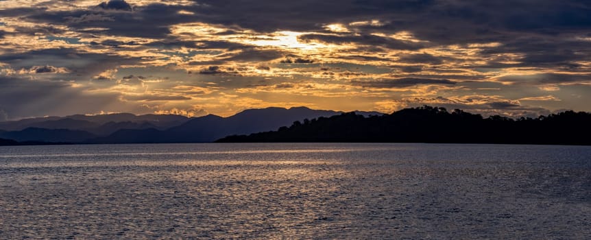 Wide panorama of Pacific Coast of Tarcoles in Carara landscape with sunset and glittering waves. Romantic sunset over sea landscape. Tarcoles, Costa Rica. Pura Vida, travel to exotic tropical country.