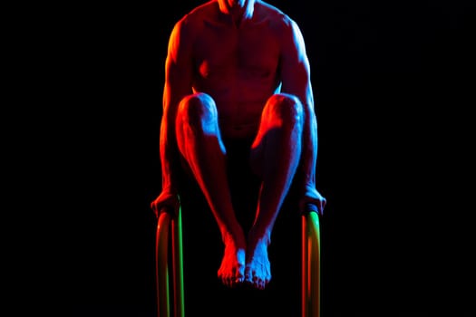 Front and side view photo of strong young man exercising on parallel bars in studio.