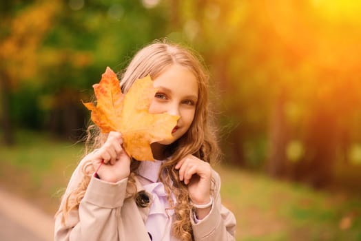 Adorable little girl with autumn leaves in beauty park