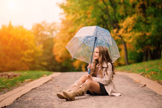 Young attractive smiling girl under umbrella in an autumn forest