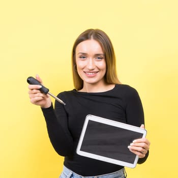 Service center. Laptop Repair. Female screwdriver unscrews laptop bolts on a yellow background