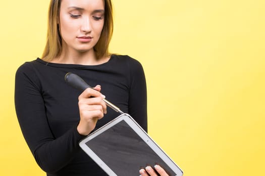 Service center. Laptop Repair. Female screwdriver unscrews laptop bolts on a yellow background