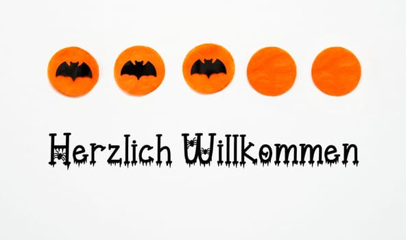 White Halloween Background With Orange Dots And Black Bats And German Text Herzlich Willkommen, Which Means Welcome In English