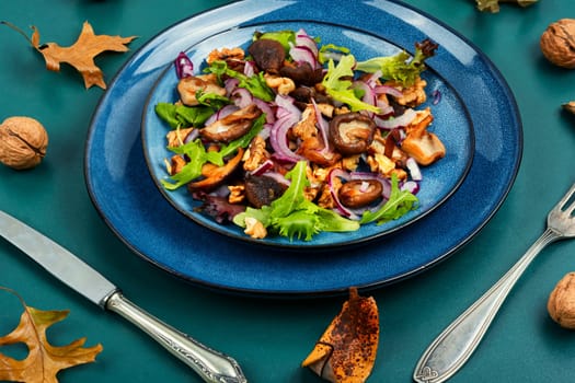 Diet salad with grilled forest mushrooms, onions, green and walnuts. Top view, copy space.