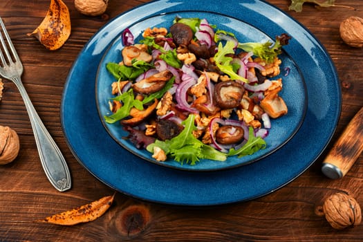 Diet salad with grilled forest mushrooms, onions, green and walnuts. Top view, copy space.