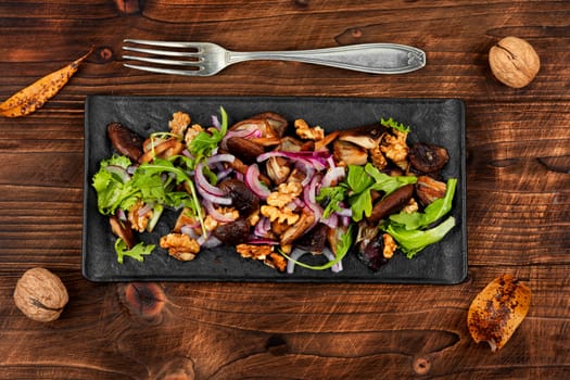 Diet salad with grilled forest mushrooms, onions, green and walnuts. Top view, copy space.