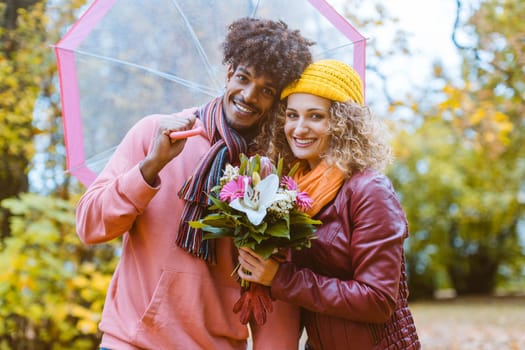Man and woman of different ethnicity hugging in fall during a walk