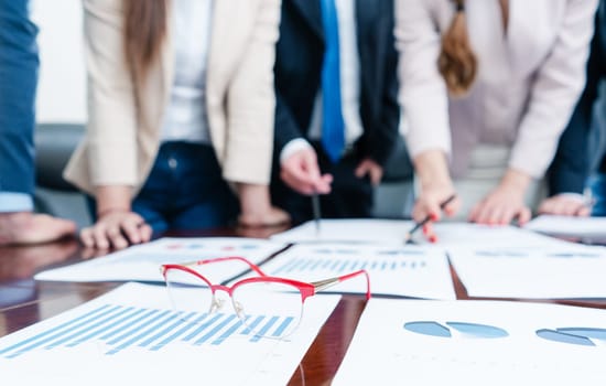 Close-up of eyeglasses with red frames on a printed bar chart showing progress during business meeting in office of company