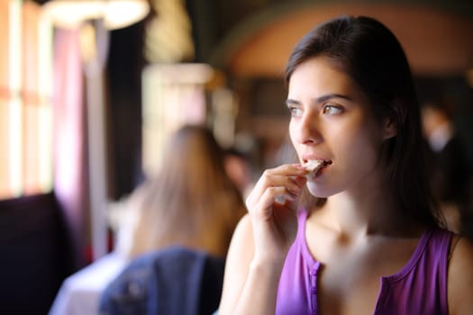 Beautiful customer eating bread in a restaurant interior