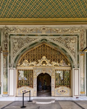 Istanbul, Turkey - May 11, 2023: Golden decorated arched entrance in painted ornate wall and green decorated ceiling at the courtyard of Dolmabahce Palace, Besiktas district