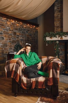 Woman sat comfortably in a wide armchair with a blanket in her country house