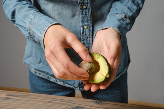Close up of female hands taking out seed from avocado