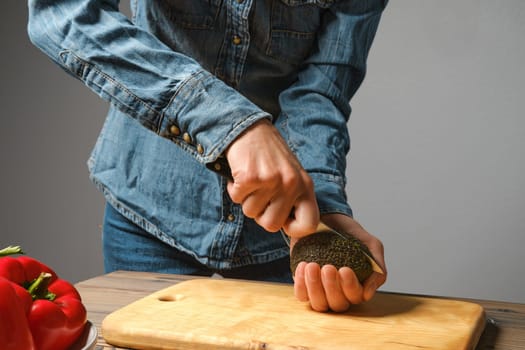 Unrecognizable woman cutting avocado with knife in the kitchen